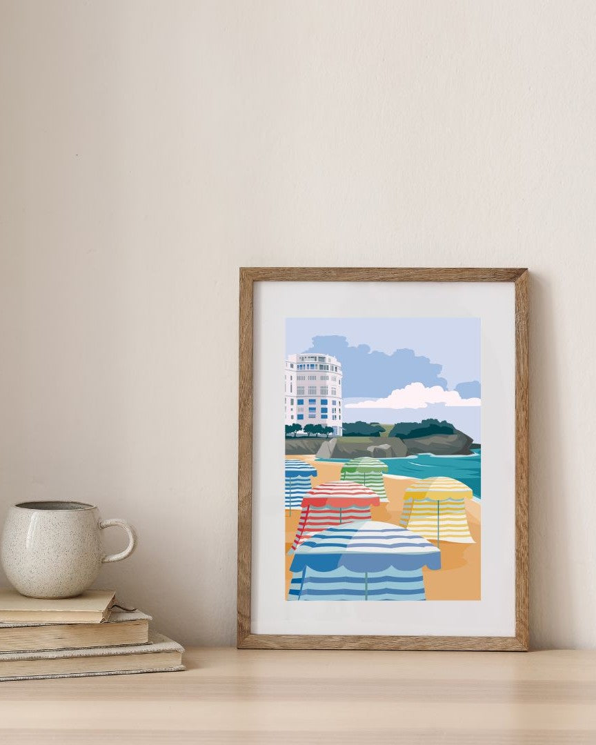 Affiche de l'hôtel avec ses parasols à Biarritz, encadrée en bois dans un décor minimaliste.