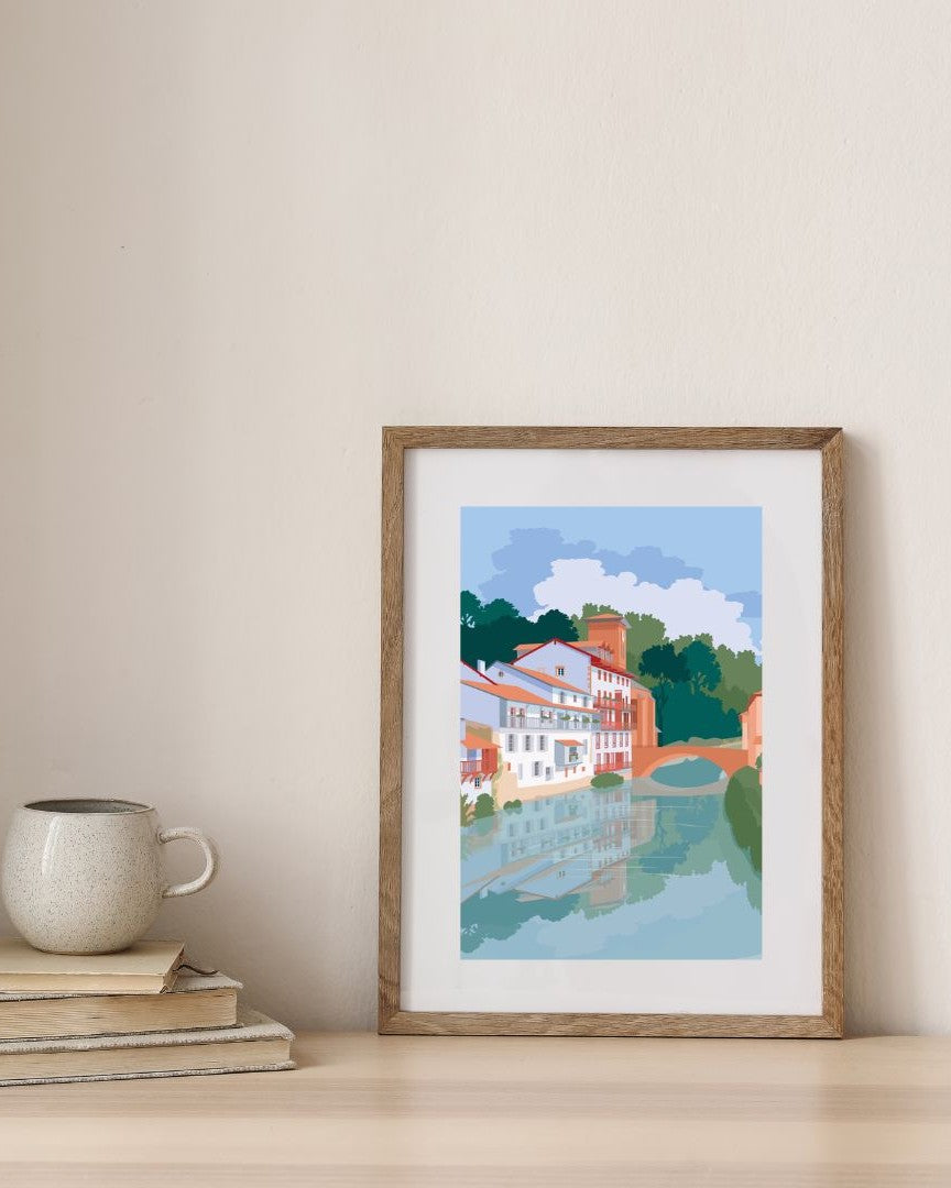 Affiche du village de Saint-Jean-Pied-de-Port dans un cadre en bois, sur fond minimaliste.